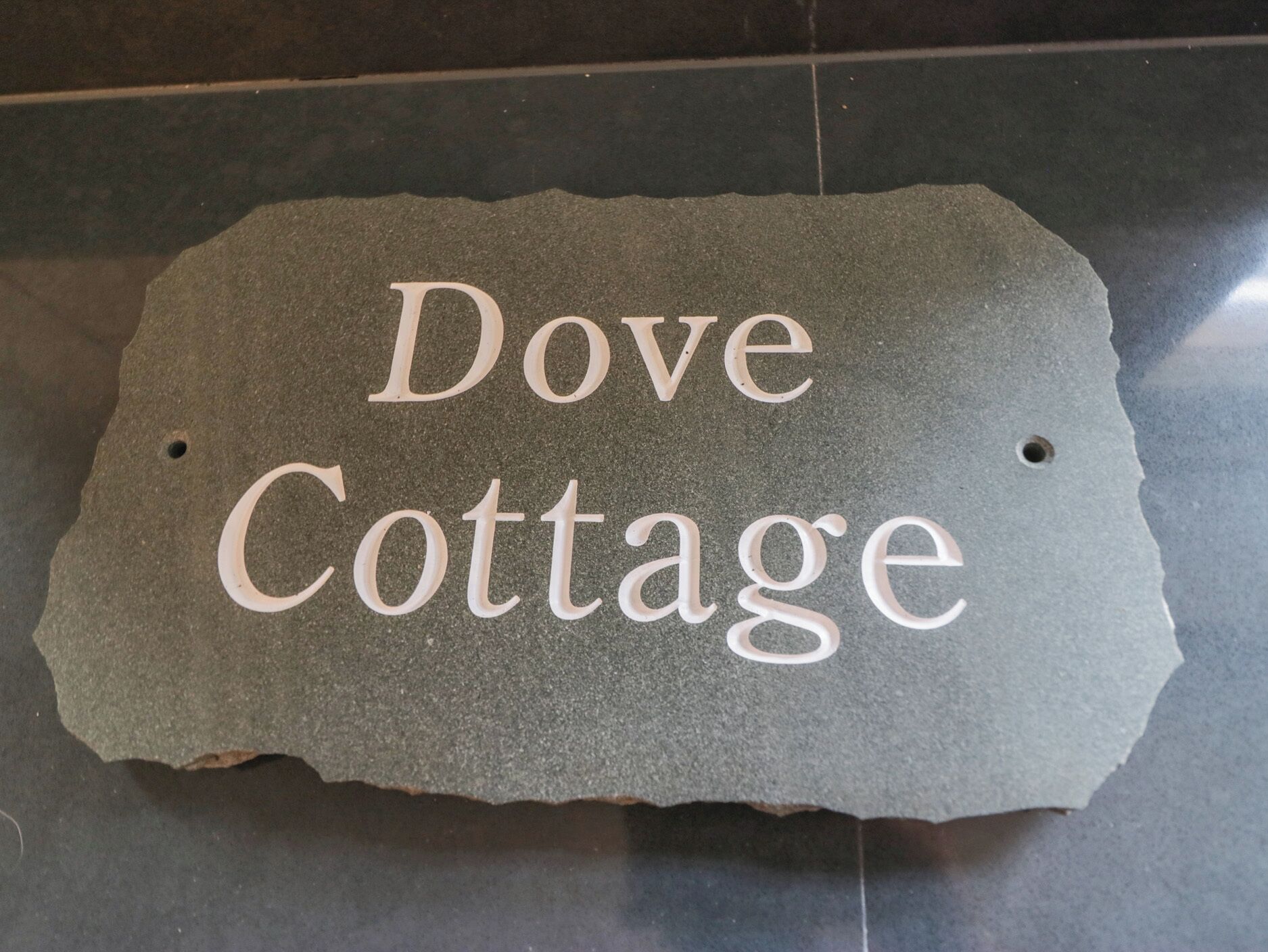 A stone sign with the text "Dove Cottage" on a dark surface.
