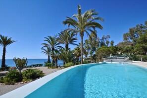 A pool with clear blue water, surrounded by palm trees and a view of the ocean. - Fantastic finca right by the sea with infinity pool (Cuevas del Almanzora)