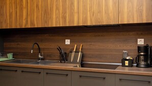 A kitchen with wooden cabinets, a stainless steel sink, a coffee maker, and a knife block. - Dioroh Suites Meteora 304 (Kalabaka)