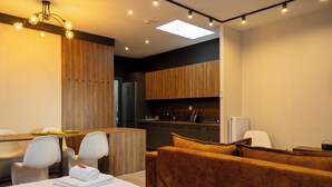 A modern hotel room with a dining area, a kitchen, and a seating area with a sofa and chairs. - Dioroh Suites Meteora 304 (Kalabaka)
