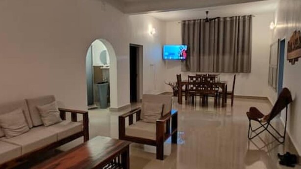 Un salon comprenant un canapé, des fauteuils, une table basse, un téléviseur et un coin repas avec une table et des chaises.