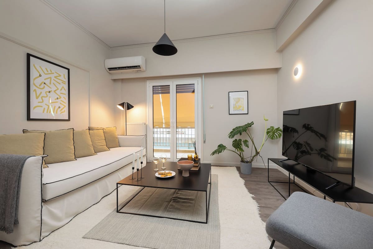 A modern living room with a sofa, coffee table, TV, and potted plants.
