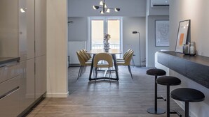 Eine moderne Küche mit Essbereich, mit Holzboden, einer zentralen Kochinsel und einer Bar mit Hockern.