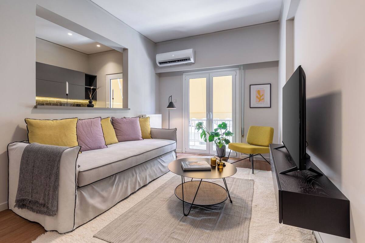A modern living room with a sofa, a coffee table, a TV, and a plant.