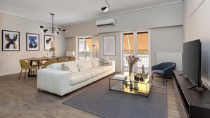 Ein modernes Wohnzimmer mit einem weißen Sofa, einem Glastisch und einem Flachbildfernseher.