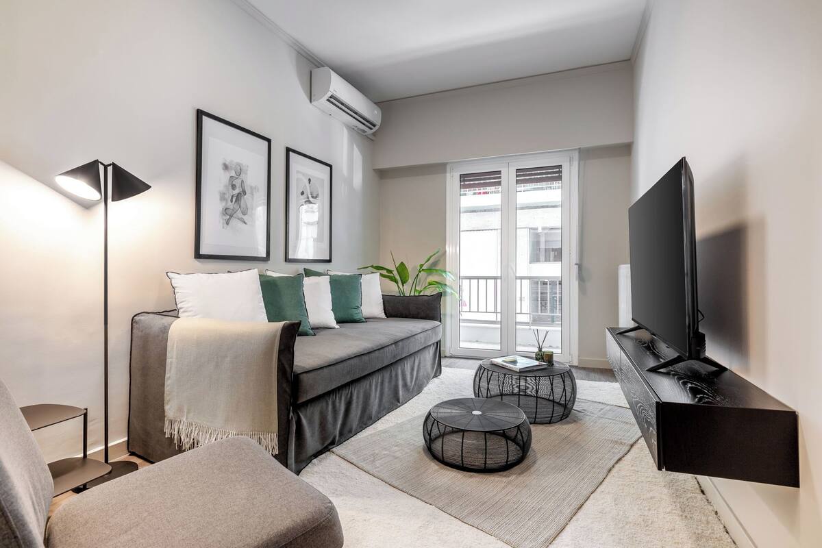 A modern living room with a sofa, a coffee table, a TV, and artwork on the wall.