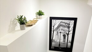 Una escalera moderna con peldaños de madera y barandillas blancas, que conduce a un rellano con una fotografía blanco y negro del Arco del Triunfo en París.