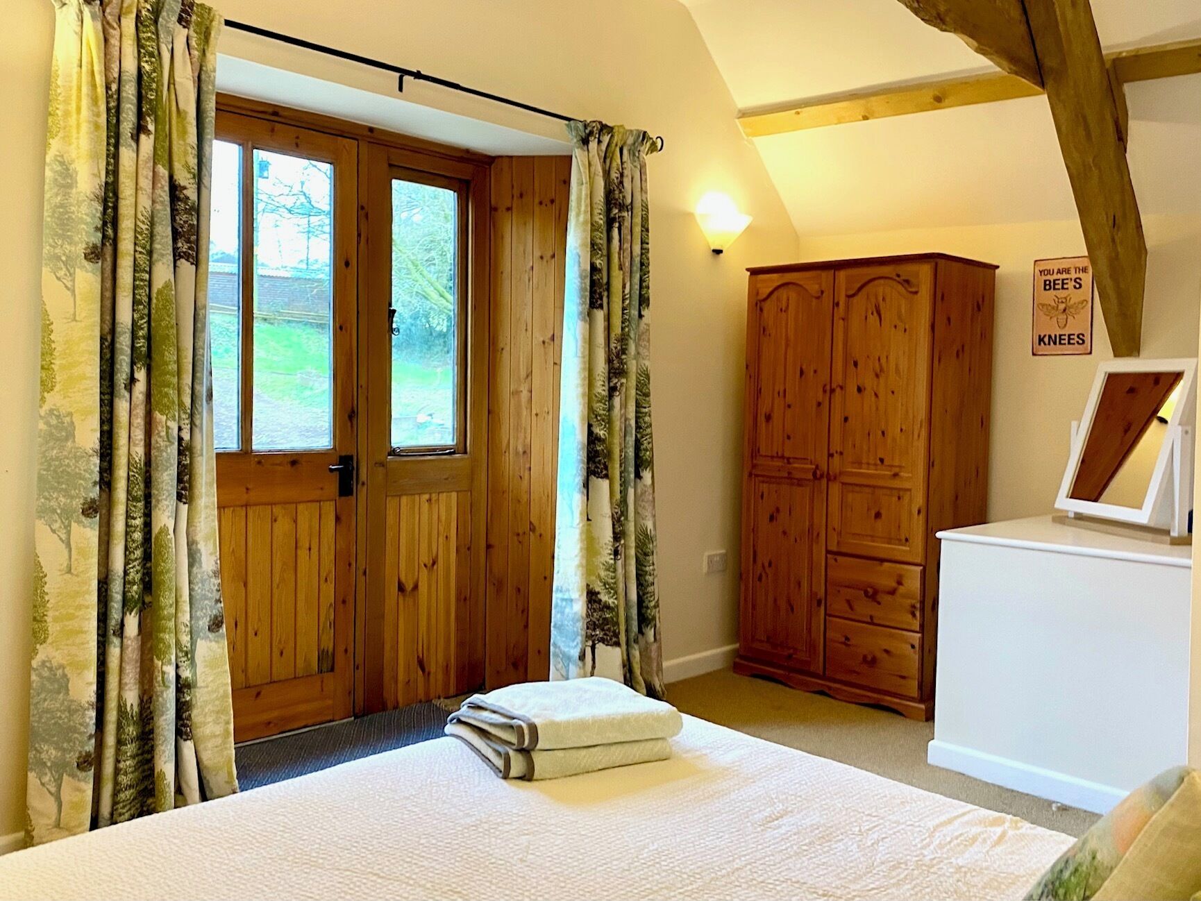 A bedroom with a wooden door, a wardrobe, a bedside table, and a sign on the wall.
