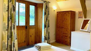 A bedroom with a wooden door, a wardrobe, a bedside table, and a sign on the wall.