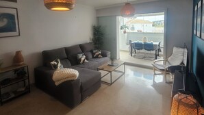 A modern living room with a sofa, coffee table, and hanging lamps. - 🌴 **Luxury Coastal Getaway – 2 Bed, 2 Bath Apartment with Pool Views** 🌴
 (Manilva)