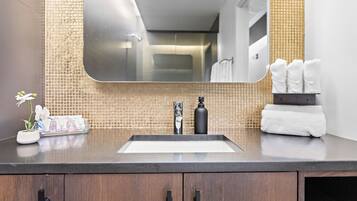 Une salle de bain avec un plan de toilette foncé, un lavabo, un miroir et un porte-serviettes.