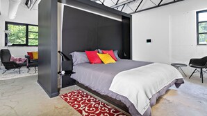 A modern bedroom with a large bed, a skylight, and a view of the outdoors.