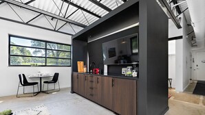 A modern kitchen with a dark wood cabinet, a built-in TV, and a dining area with two chairs and a table.