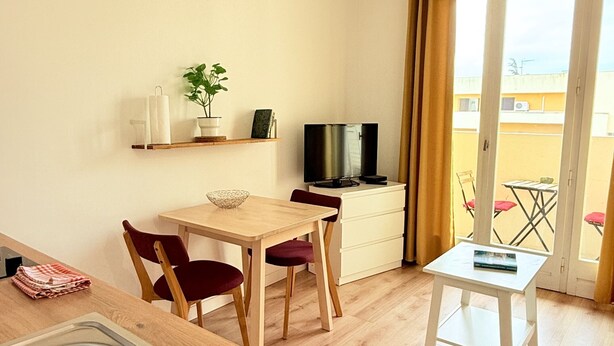 A compact living space with a kitchenette, dining area, and a small TV.