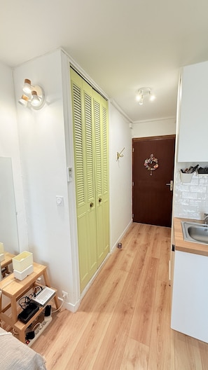 A small, compact kitchen with a wooden floor, a white refrigerator, and a wooden cabinet.