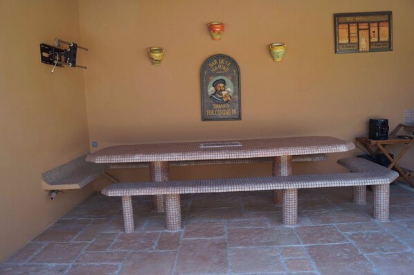 A picnic table with a bench, a wall-mounted sign, and a tiled floor.