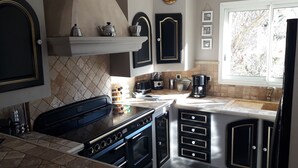 Una cocina equipada con estufa, horno y diversos electrodomésticos. Se observa una ventana con vistas a árboles.