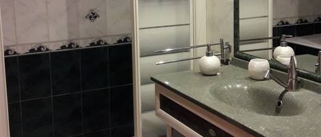 A bathroom with a shower, a sink, and a mirror.