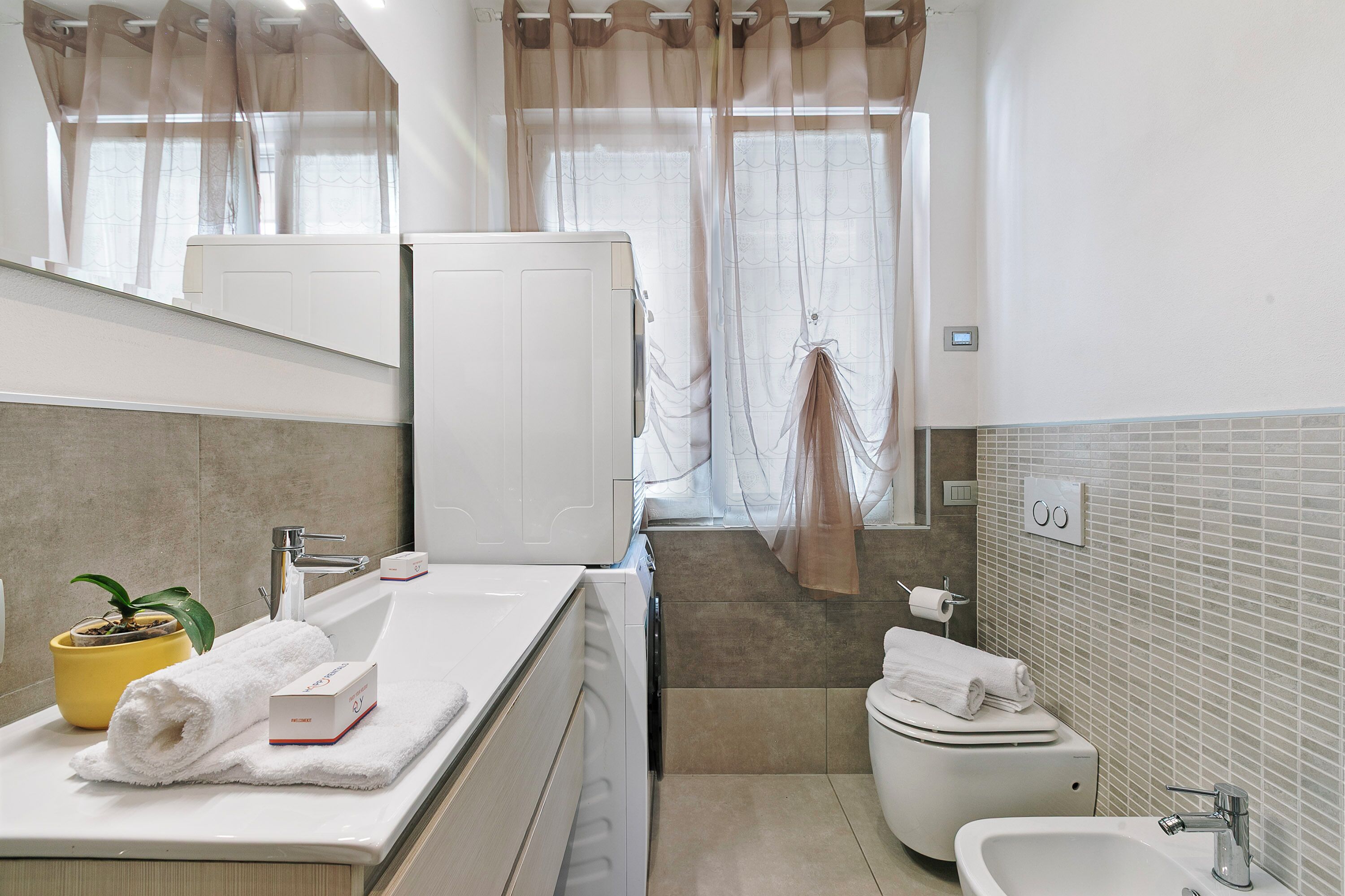 A modern bathroom with a sink, mirror, and toilet.