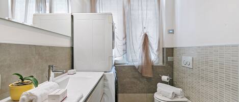 A modern bathroom with a sink, mirror, and toilet.