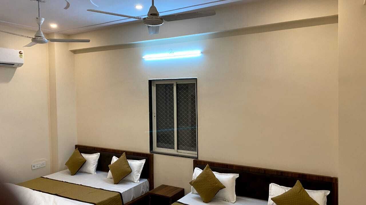 Une chambre d’hôtel avec deux lits, une fenêtre, des ventilateurs de plafond et un luminaire au plafond.
