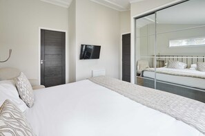 A bedroom with a large bed, a television, and a sliding door leading to another room. - Host Stay Henry Bolckow Lodge (Middlesbrough)
