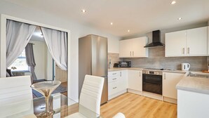 A modern kitchen with white cabinets, a stainless steel refrigerator, a microwave, and an oven. - Host Stay Venture Park Villas (Kettering)