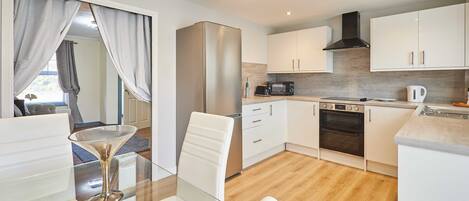 A modern kitchen with white cabinets, a stainless steel refrigerator, a microwave, and an oven.