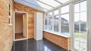 A room with a brick wall, a large window, and a door leading to another room. - Host Stay Venture Park Villas (Kettering)