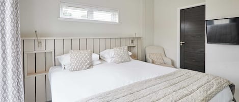 A neatly arranged bedroom with a bed, a television, and a window.