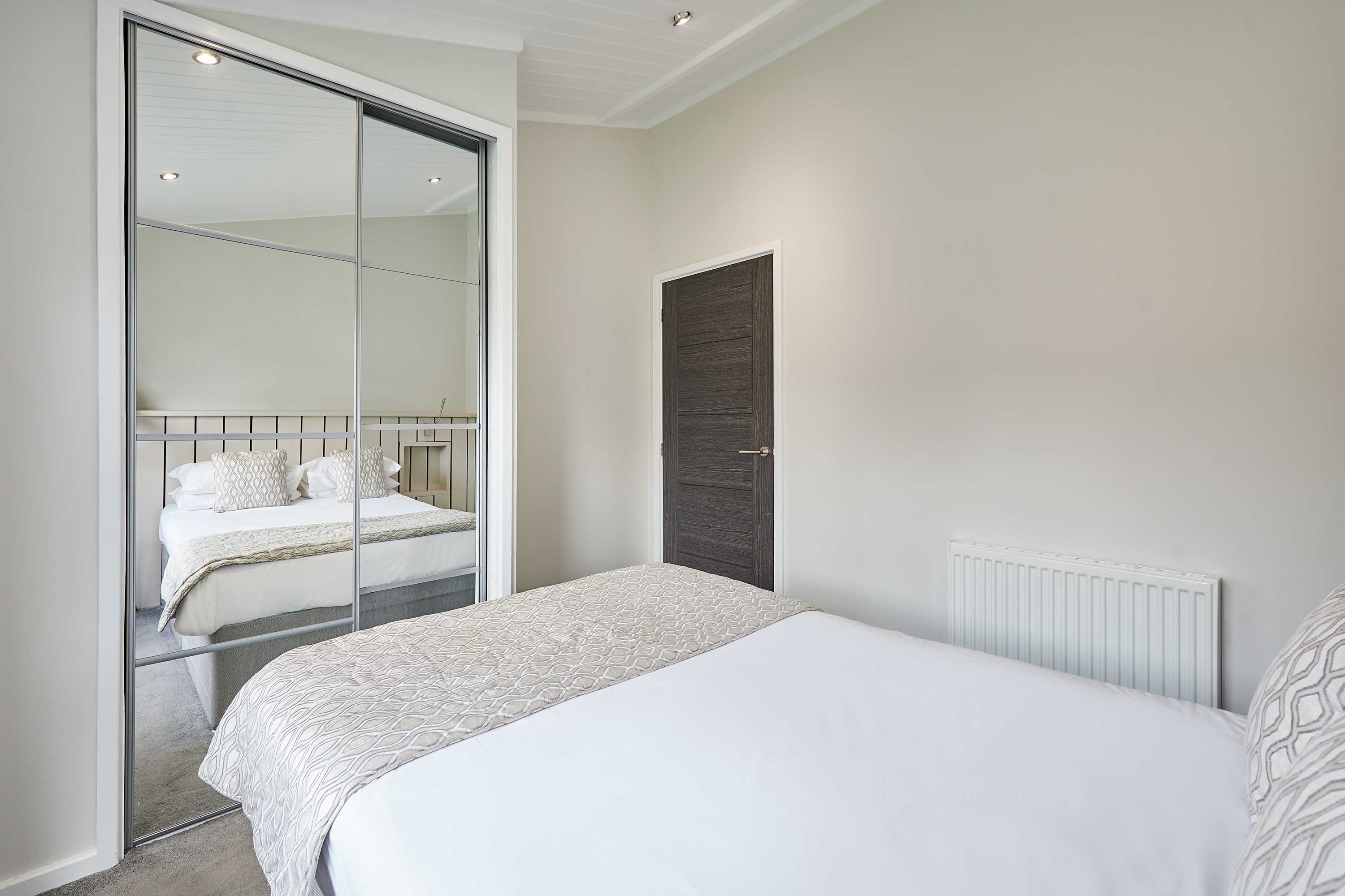 A bedroom with a bed, a sliding door, a radiator, and a dark wooden door.