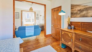 A cozy living room with a blue sofa, wooden furniture, and a painting on the wall. - Host Stay Gray Street (Whitby)