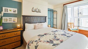 A bedroom with a large bed, a dresser with drawers, a nightstand with a lamp, and a window with curtains. - Host Stay Gray Street (Whitby)