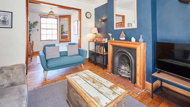A living room with a blue wall, a fireplace, a sofa, a coffee table, and a television. - Host Stay Gray Street (Whitby)