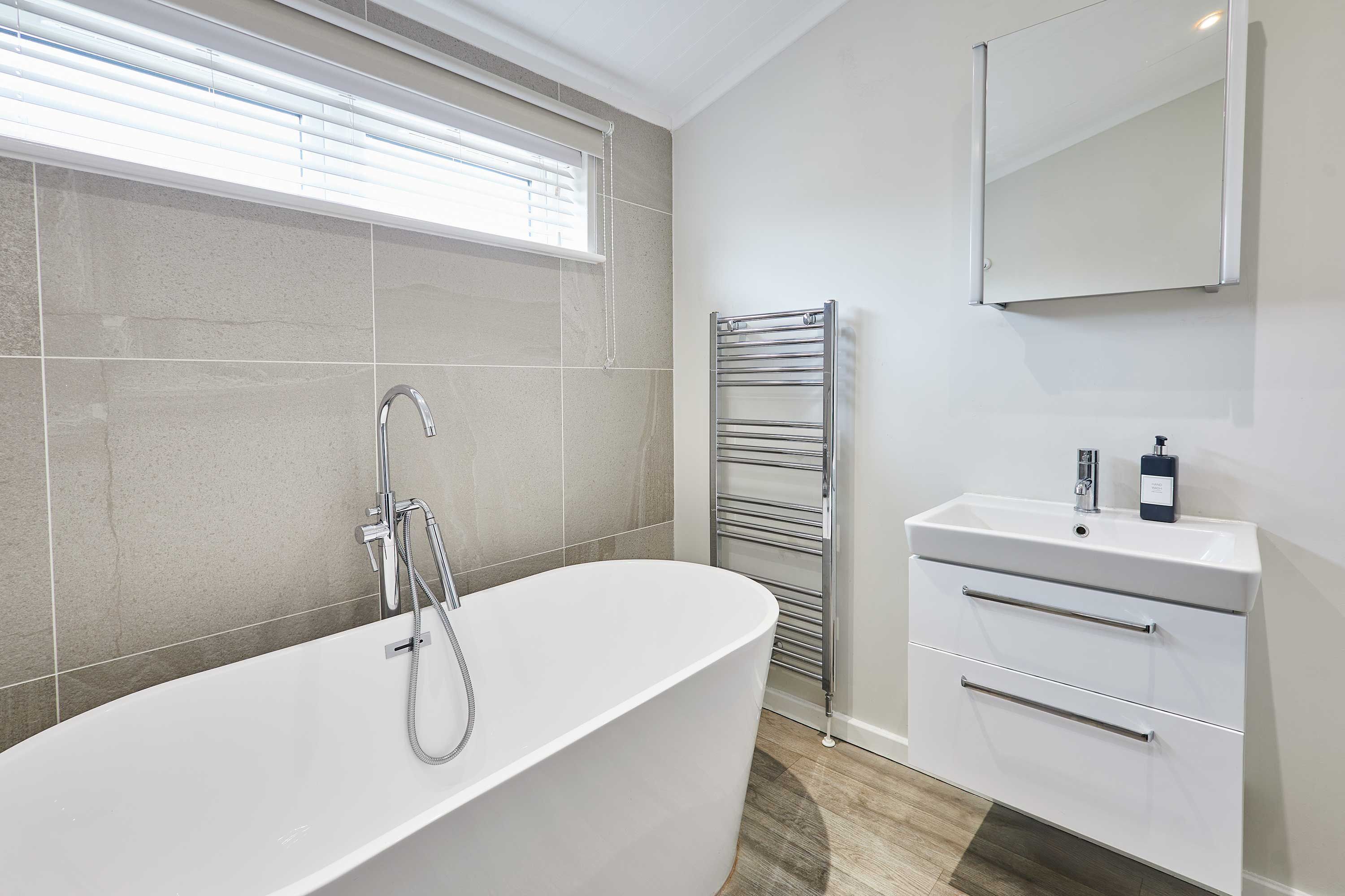 A modern bathroom with a freestanding bathtub, a built-in sink, and a towel rack.
