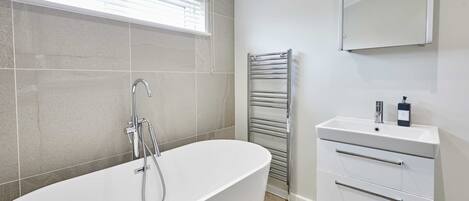 A modern bathroom with a freestanding bathtub, a built-in sink, and a towel rack.