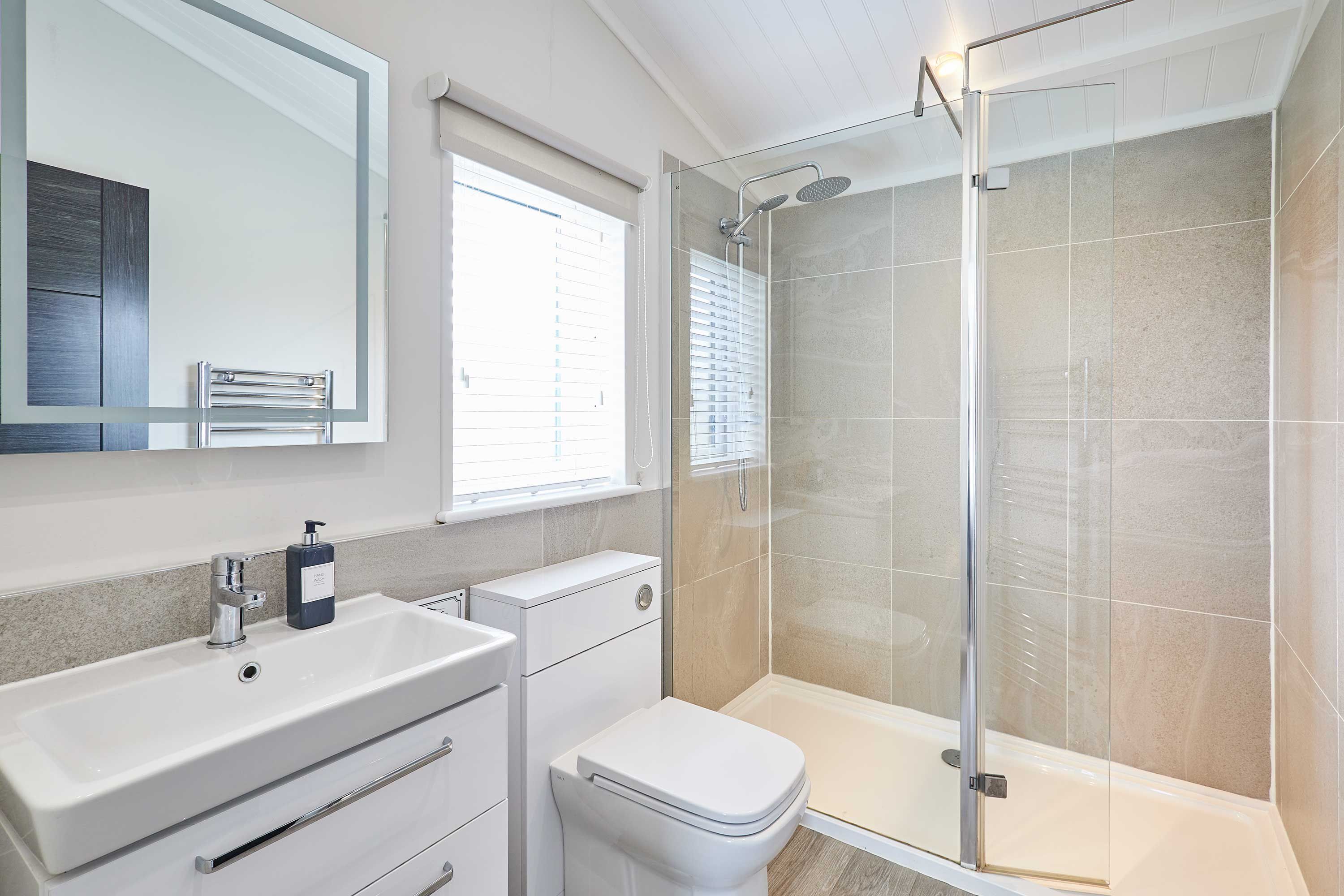 A modern bathroom with a glass-enclosed shower, a white sink, and a toilet.