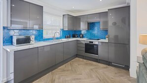 A modern kitchen with grey cabinets, a microwave, a kettle, and a sink. - Host Stay Farm Road (Hove)