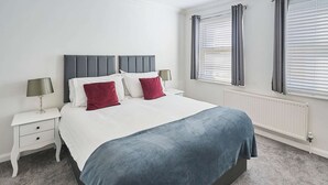 A neatly arranged bedroom with a bed, two bedside tables, and a window with blinds. - Host Stay Farm Road (Hove)
