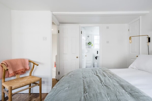 A bedroom with a bed, a chair, a bedside table, a lamp, and a door leading to a bathroom. - Central Georgian Townhouse With Free Parking (Bath)