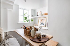 A bright, white room with a wooden table, a window with plants, and a shelf with various items. - Central Georgian Townhouse With Free Parking (Bath)