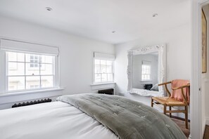 A bedroom with a bed, two windows, a radiator, a mirror, and a chair. - Central Georgian Townhouse With Free Parking (Bath)