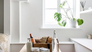 Ein gemütlicher Winkel mit einem Holztisch, der eine Flasche, ein Glas und einen Korbwägelchen trägt.