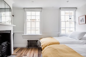 A bedroom with two beds, a radiator, and a fireplace.