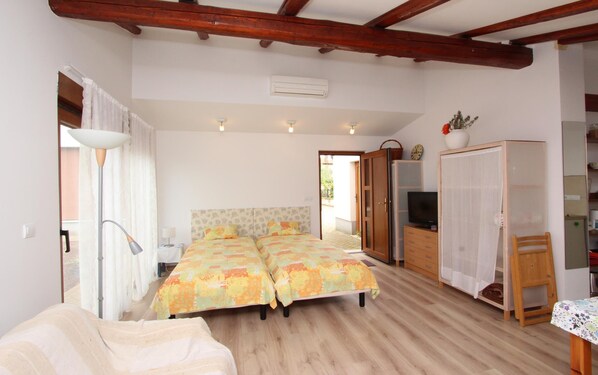 A bedroom with two beds, a wardrobe, a television, and a small table.
