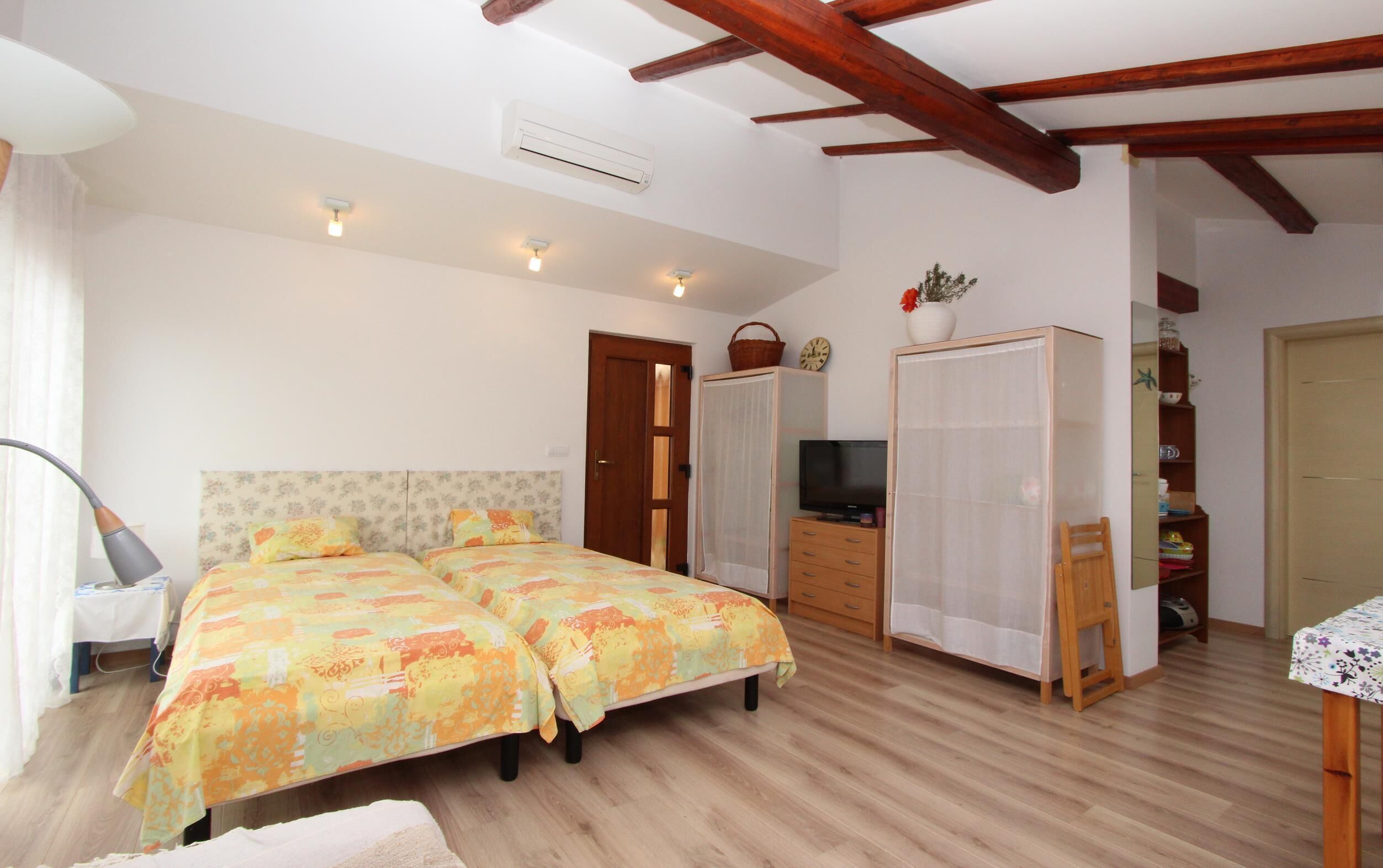 Un dormitorio con dos camas, televisión, armario y una pequeña mesa.