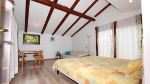 A bedroom with a wooden ceiling, a bed with a colorful bedspread, a desk with a chair, a small table, and a window with curtains. - Studio Rovinj Home (Rovinj)