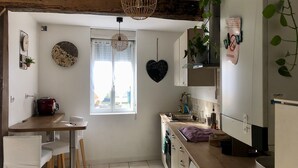 Una cocina compacta con una mesa de madera, taburetes de bar, lavadora y ventana con vistas.