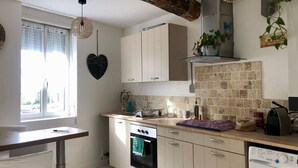 Una cocina con ventana, una decoración con forma de corazón, armarios, estufa, lavadora y luces colgantes.