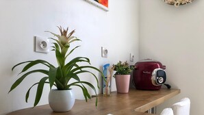 Una encimera de cocina con una planta en maceta, un electrodoméstico rojo y una libreta.
